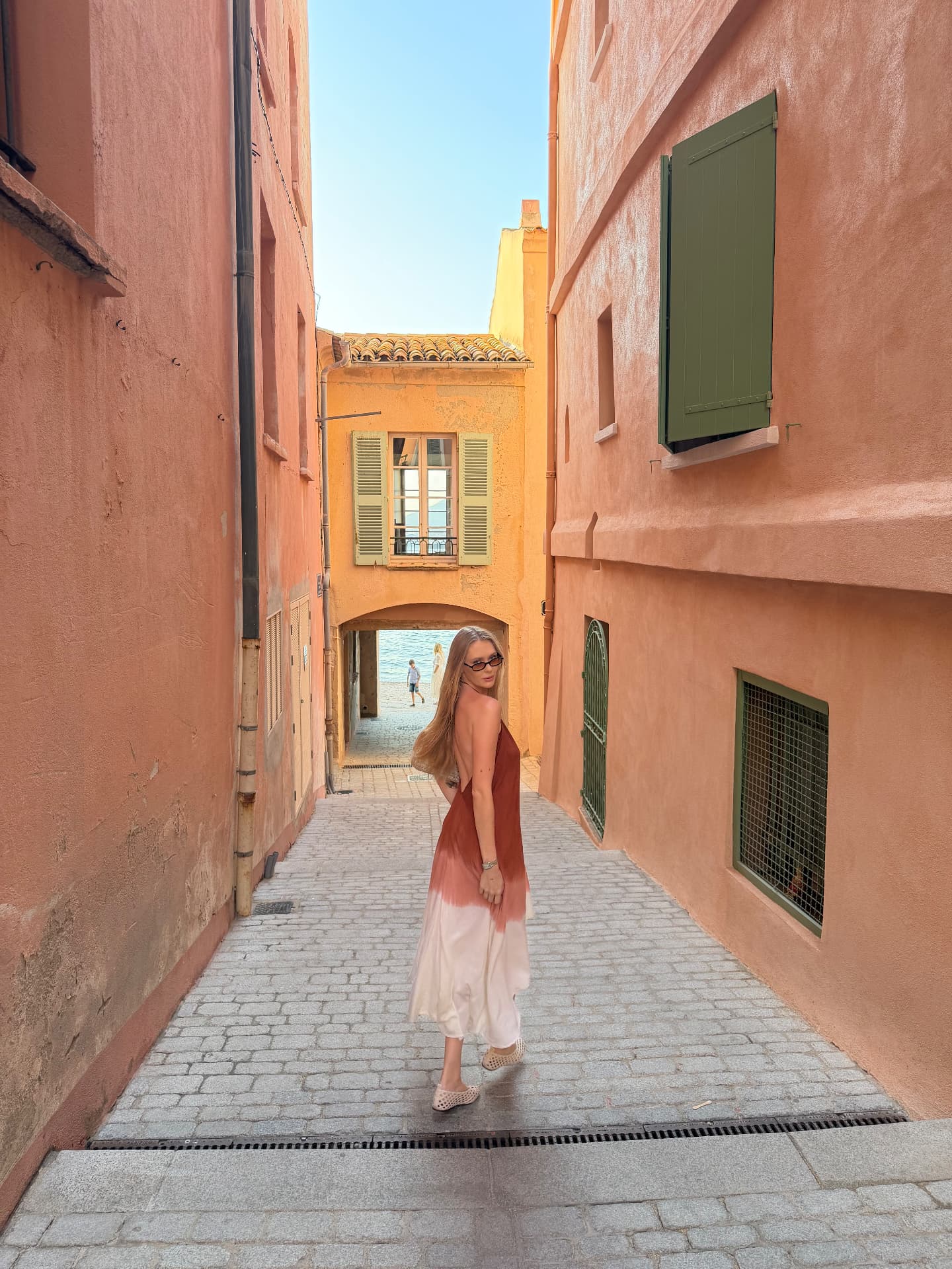 Natalie walking through a sunlit French Riviera street